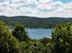 A lake surrounded by lush greenery and hills under a partly cloudy sky.