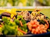 A plate with shredded meat, cubed yellow and purple vegetables, mixed greens, and diced tomatoes, arranged in separate sections.