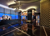 Luxurious hotel lobby with modern decor, featuring a glossy black floor, unique ceiling design, large windows, decorative circular sculptures, and a seating area in the distance.