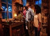 A family of three looking at magical creatures through a window above a cluttered dest in a dusty room in at set on the Warner Bros. Studio Tour Hollywood.