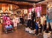 Shoppers browse merchandise and clothing displays, including superhero outfits on mannequins, in a brightly lit retail store.