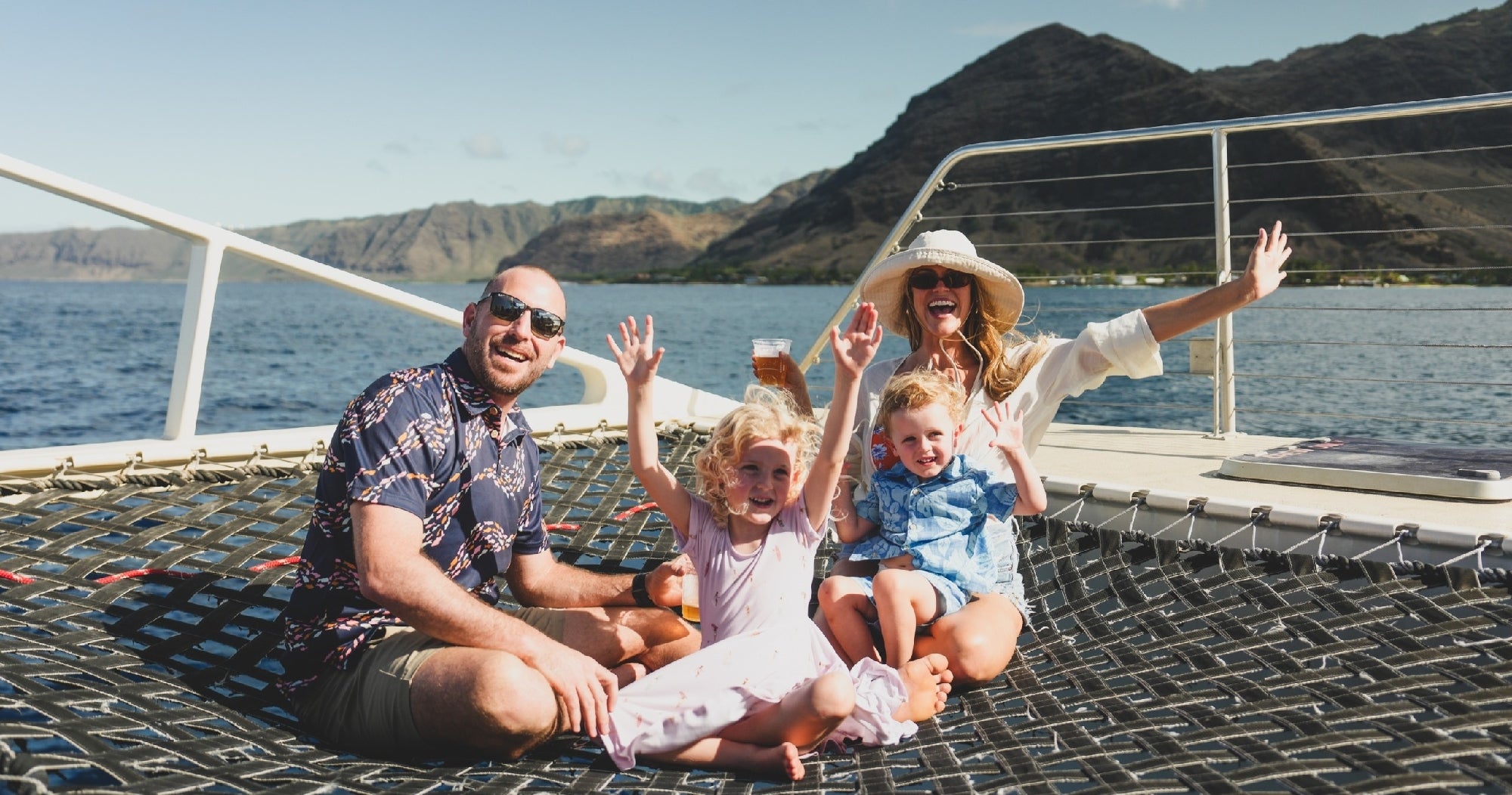 Family enjoying catamaran cruise along West Oahu coastline
