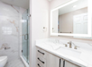 Modern bath area featuring a sink with a lighted mirror, a walk-in shower, and plush towels.