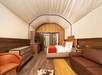 A large bed and a sofa bed inside a glamping tent.