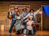 Five musicians on stage holding their instruments and smiling at WhoDunnit Hoedown Murder Mystery Dinner Show in Branson, Missouri.