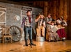 A young boy singing into a microphone with a band behind him at WhoDunnit Hoedown Murder Mystery Dinner Show in Branson, Missouri.