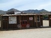An old building with a small awning with a red wagon painted on the side and a several signs warning tourists.
