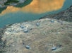 An aerial view of the Colorado River and picnic benches with tourist with four helicopters parked near them.