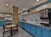 Breakfast area with blue cabinetry, a soda dispenser, tables with chairs, and various breakfast items displayed on a countertop.