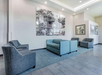 Modern lobby with gray and blue seating, a large black-and-white mural, and sleek tiled flooring.