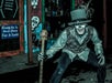 Person in a skeleton face paint and top hat, holding a staff, poses in front of a painted wall with skeletons and a sign reading "Come on in and shop for a spell.