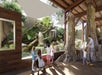 A group of children and adults observe an indoor aquarium exhibit featuring lush plants, rocks, and water, within a building with wooden beams and large windows.
