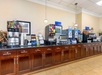Self-serve breakfast buffet with beverage dispensers, coffee station, and a variety of breakfast items on a wooden counter.
