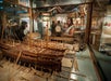 A person holding a baby, looking at a diorama depicting a colonial shipyard at Independence Seaport Museum
