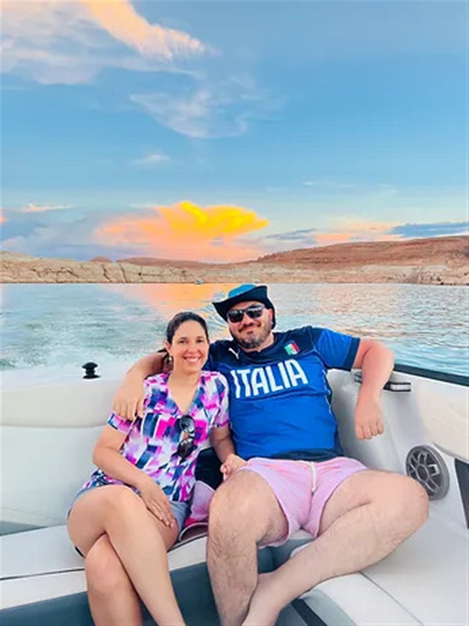 Couple taking photos in the boat with sunset background.