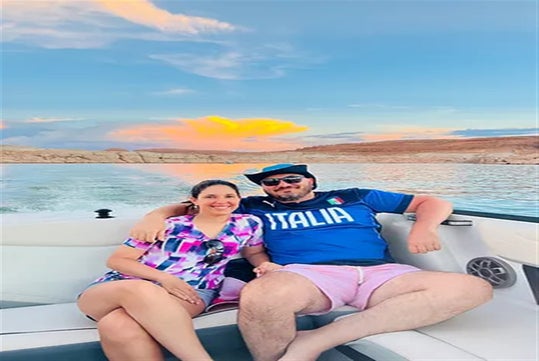 Couple taking photos in the boat with sunset background.