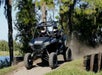 Two guests come up a small hill on a trail in their all terrain vehicle