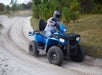 Guest drives a blue Polaris ATV around a curve