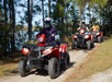 Three guests wear safety helmets while riding red ATVs
