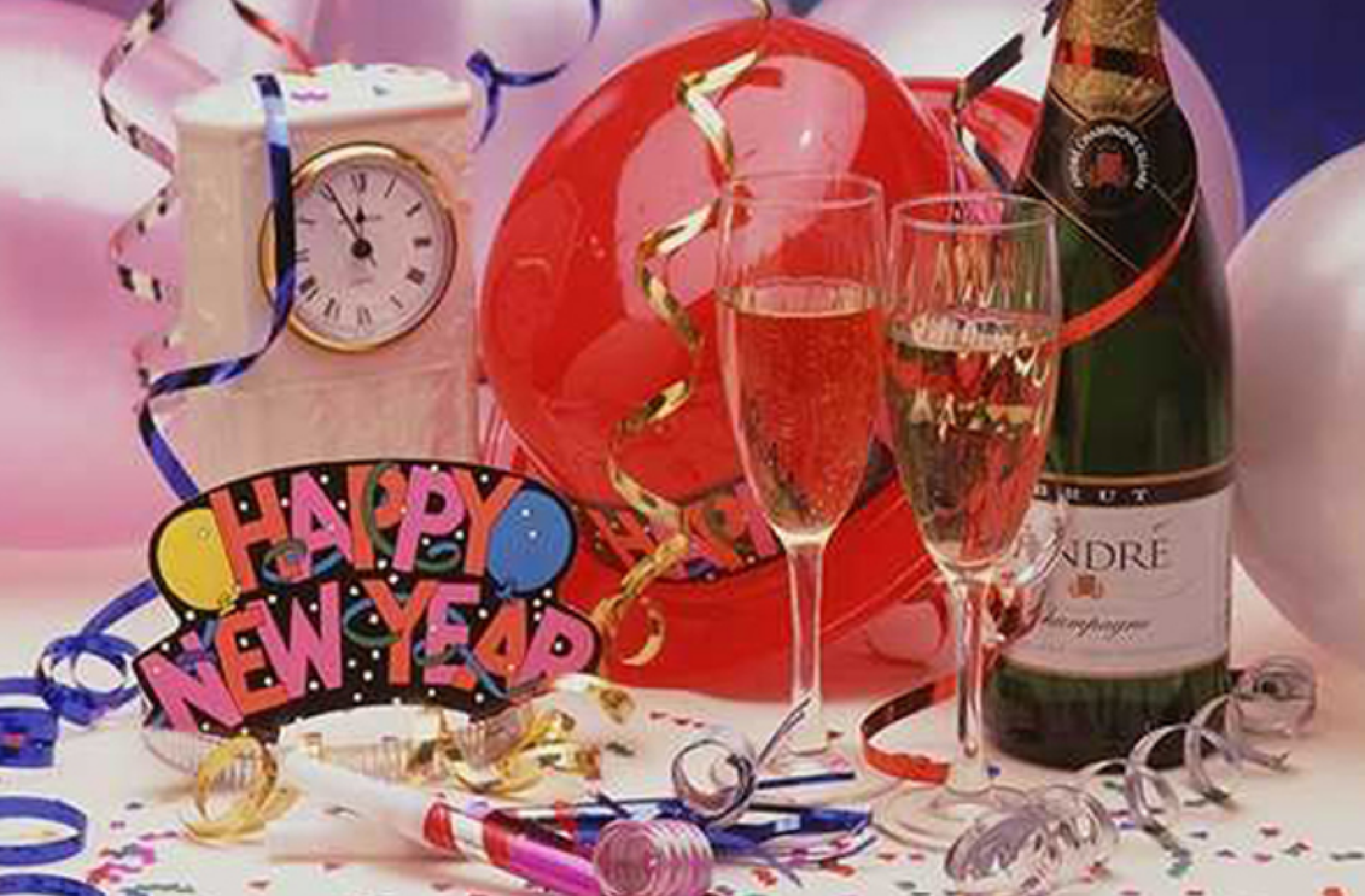 New Year's celebration scene with champagne bottle, two filled glasses, balloons, confetti, clock, noisemakers, and a "Happy New Year" mask on a table.