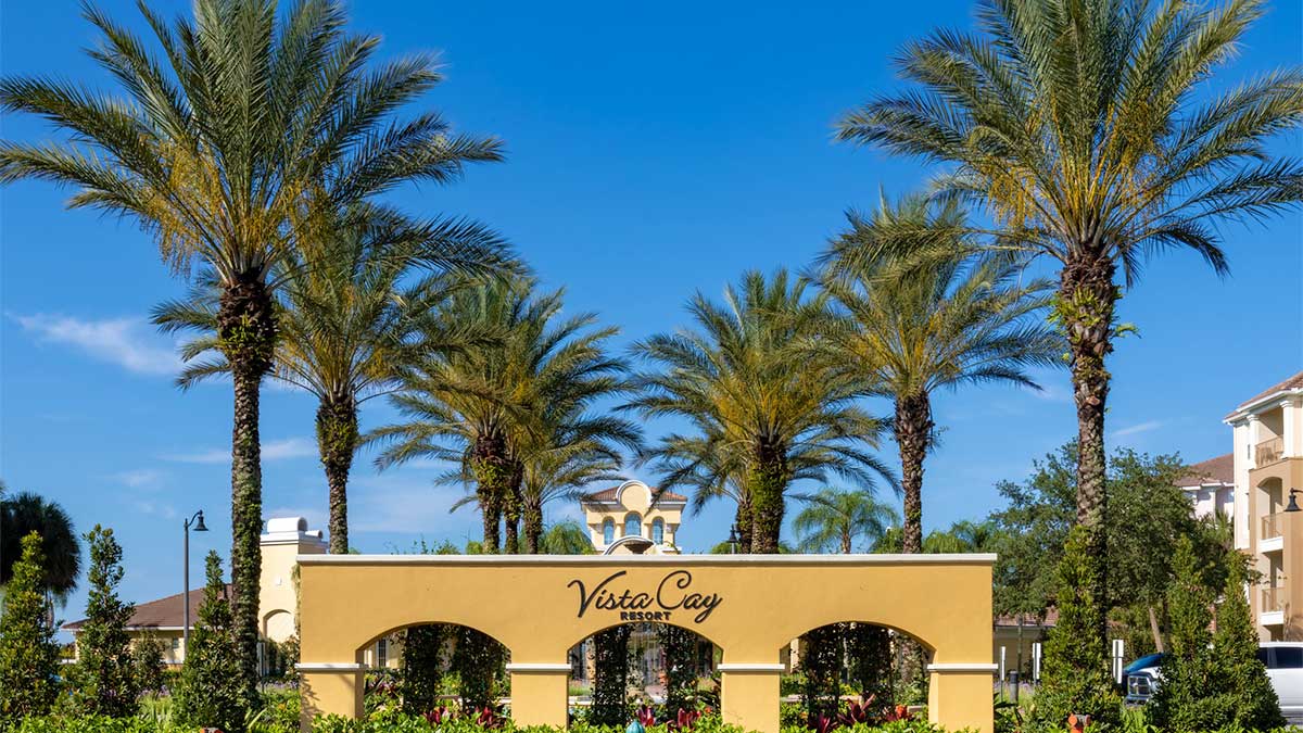 Entrance to Vista Cay Resort in Orlando, Florida, with palm trees and sunny blue sky.