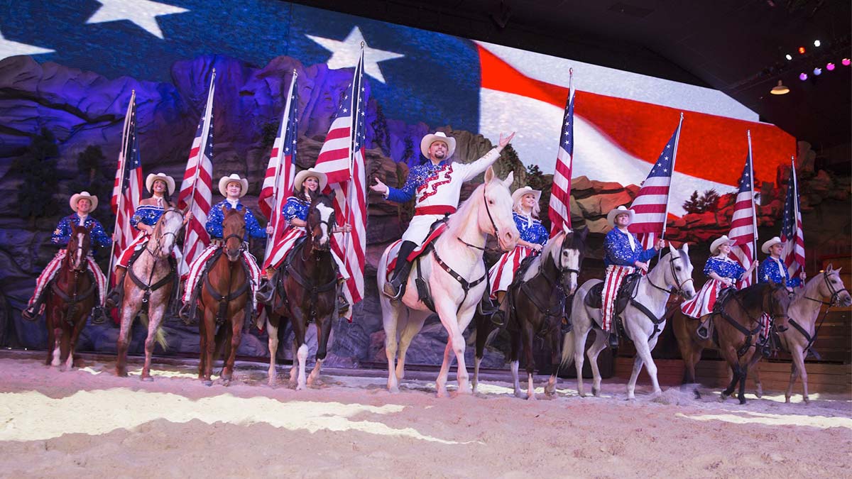 Performers on horseback holding American flags at Dolly Parton’s Stampede.