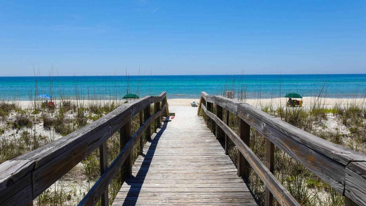 Wooden boardwalk leading to a pristine beach with turquoise water in Destin, Florida.