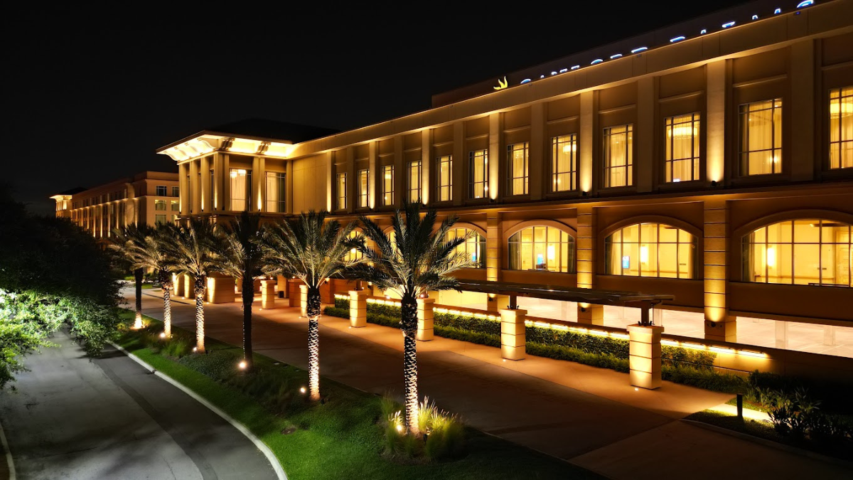 Nighttime view of the Gaylord Palms Resort in Orlando, Florida, illuminated with elegant lighting and palm trees lining the entrance.