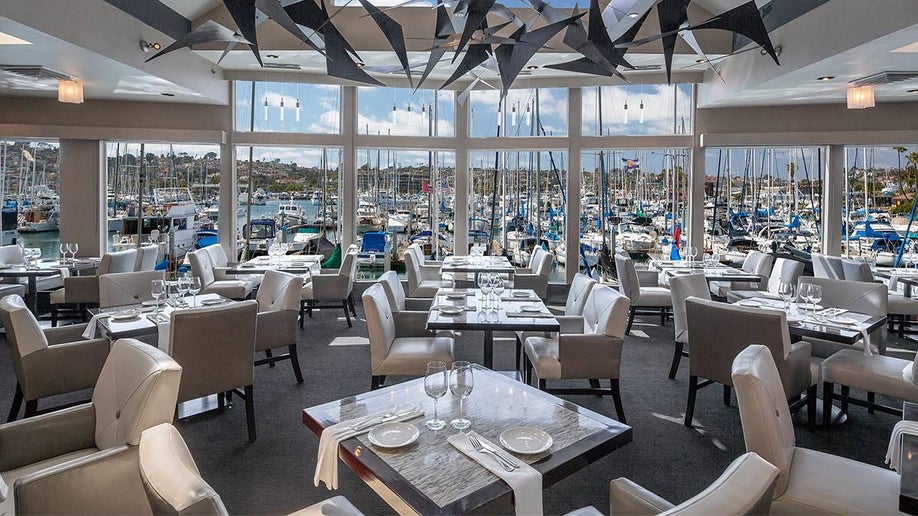 interior view of dinning room with large windows looking at sailboats inside of Humphrey’s Restaurant in San Diego, California, USA