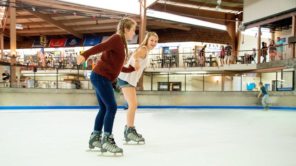 friends holding hands skating on ice skating rink together in Ober Gatlinburg Ice Skating in Gatlinburg, Tennessee, USA