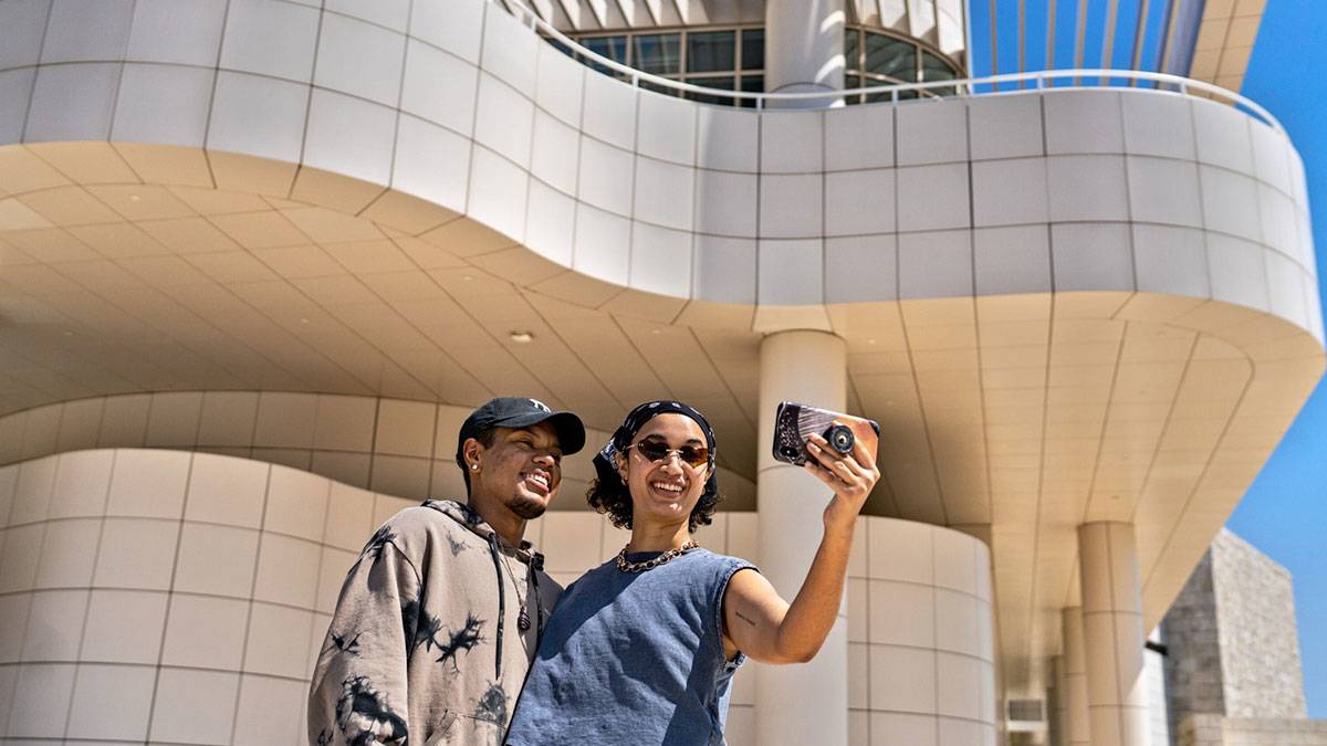 couple taking selfie with phone at exterior of The Getty Center in Los Angeles, California, USA