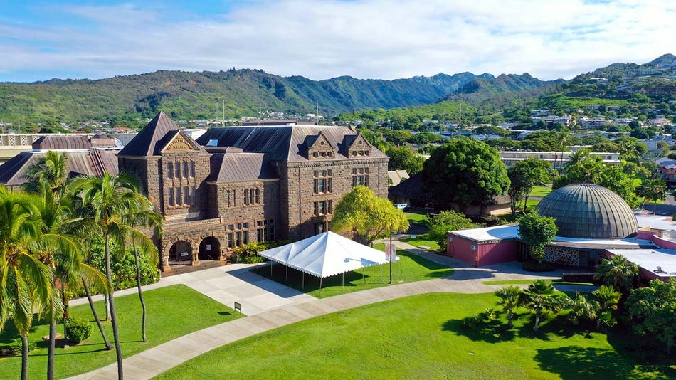 exterior ground view of Bishop Museum with palm trees and blue skies in Oahu, Hawaii, USA