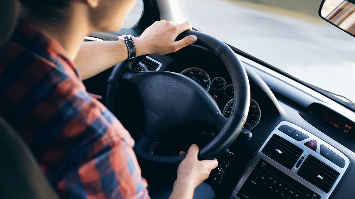 Person in a flannel shirt driving a black interior vehicle
