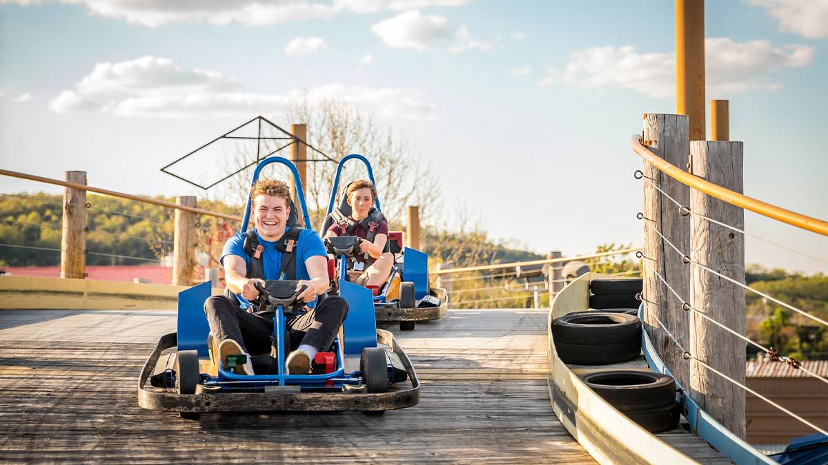 Two boys riding go karts on a sunny day in Branson, Missouri, USA