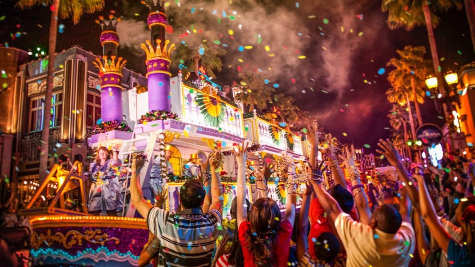 Close up of the Universal Studios Mardi Gras Parade with a huge float decorated with greens, yellows, and purple plus a large crowd around the float in Orlando, Florida, USA