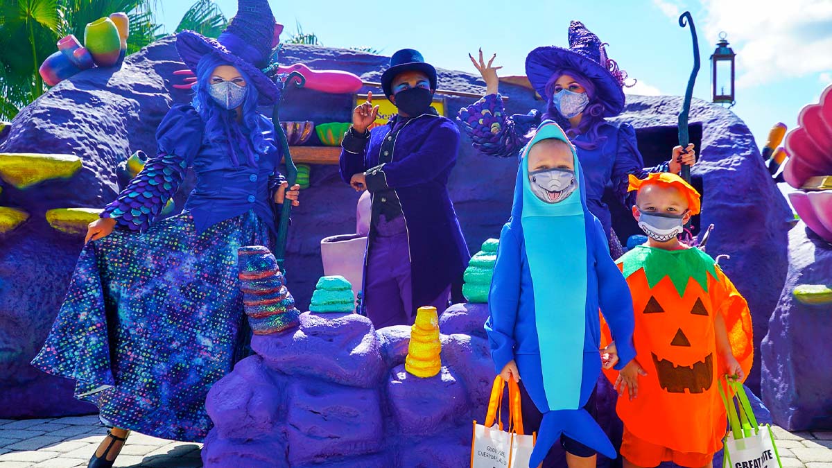 people in colorful halloween costumes with colorful purple rocks in background at Seaworld Orlando Spooktacular during sunny day in Orlando, Florida, USA