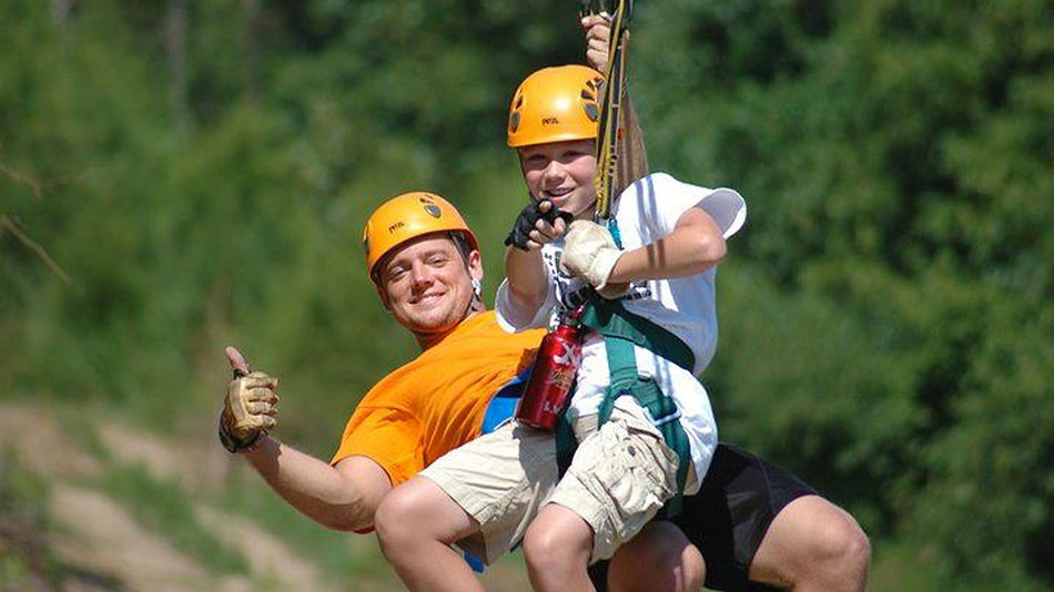 father and son ziplining tandem through trees at Ziplining Tandem at Adventure Ziplines of Branson in Branson, Missouri, USA