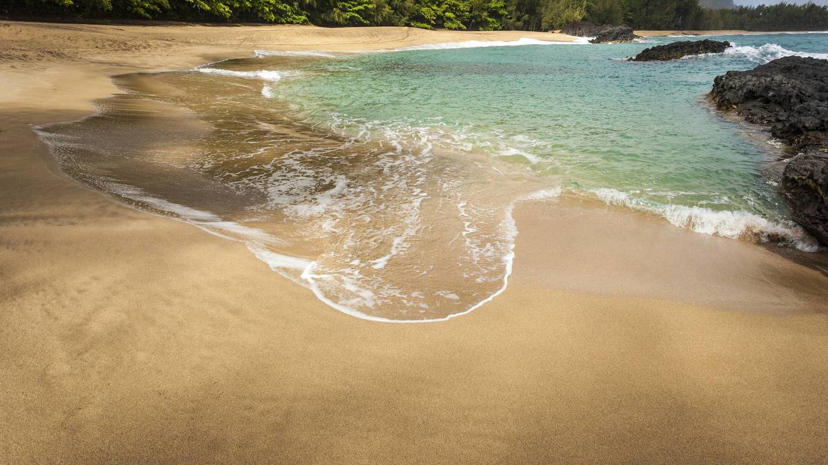 ground view of sandy beach and ocean view at Hideaway Beach in Kauai, Hawaii, USA