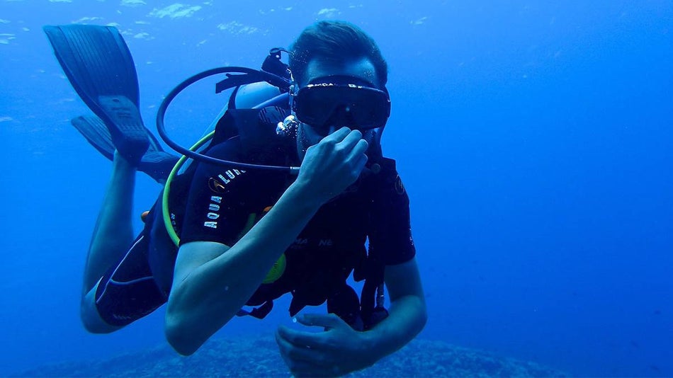 man underwater SCUBA diving in blue water