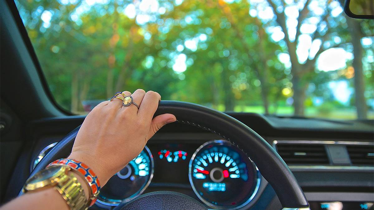 woman's hand on steering wheel inside of a car