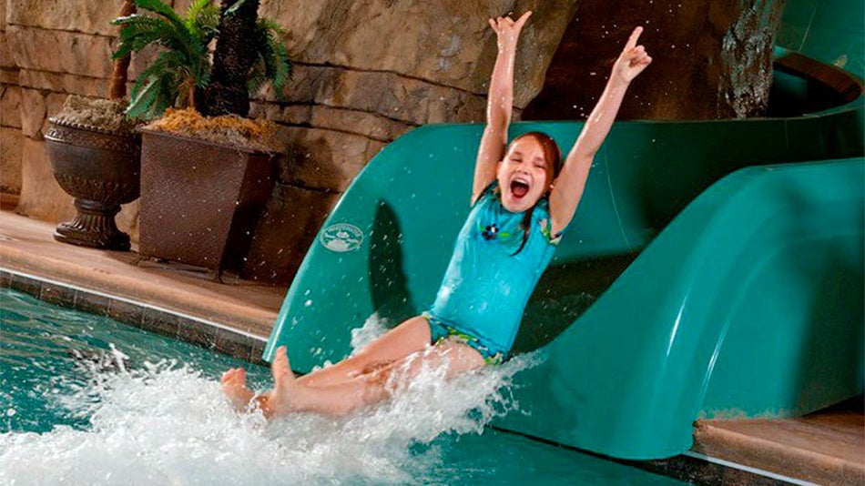 girl sliding down green slide at Welk Resorts Branson The Lodges at Timber Ridge in Branson, Missouri, USA