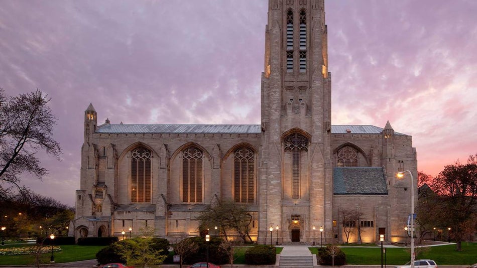 Exterior view of Rockefeller Memorial Chapel at University of Chicago with a light purple and pink sunset behind it in Chicago, Illinois, USA