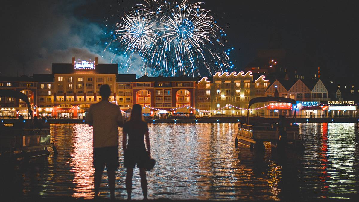 couple standing by water watching fireworks over Disney's Boardwalk in Orlando, Florida, USA