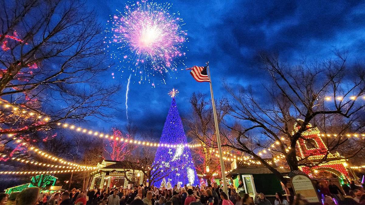 People surrounding a large Christmas Tree with fireworks going off over their heads at Silver Dollar City in Branson, Missouri, USA