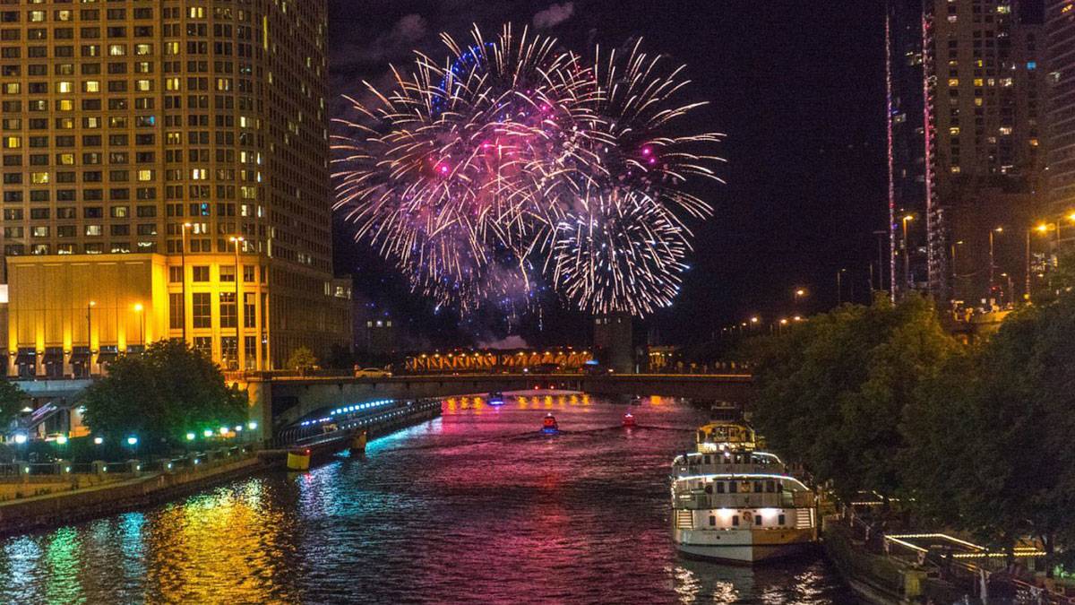 red and purple fireworks over Chicago River at night in downtown Chicago, Illinois, USA