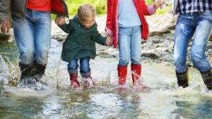 family splashing through stream with rain boots on
