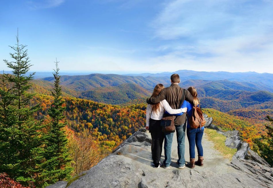 family standing together overlooking smoky mountains in fall