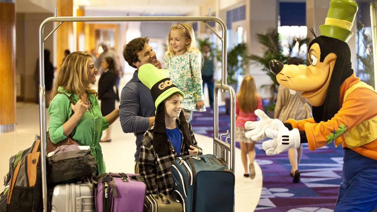 goofy greeting family of four in lobby with suitcases at Disneyland Hotel in Los Angeles, California, USA