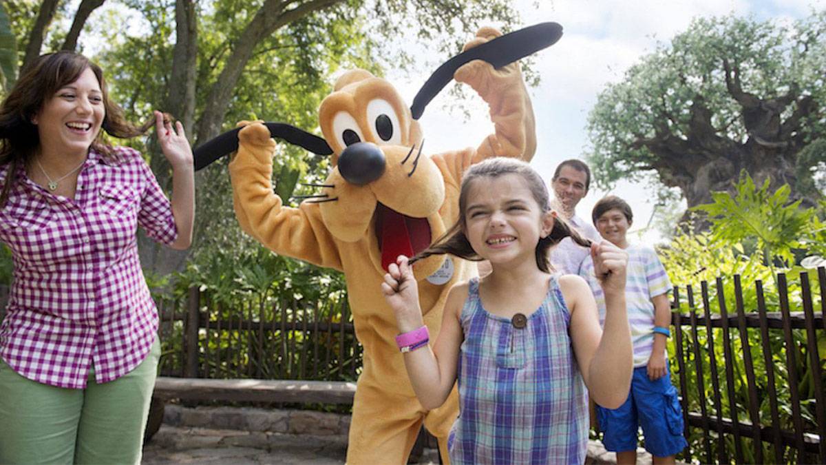 family posing for photo with pluto at walt disney world