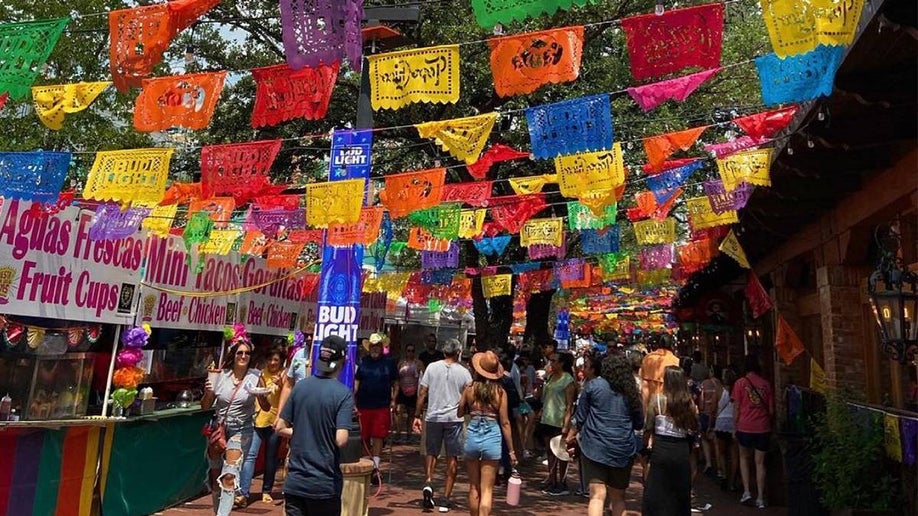 colorful flags over crowds of people walking through Market Square El Mercado in San Antonio, Texas, USA